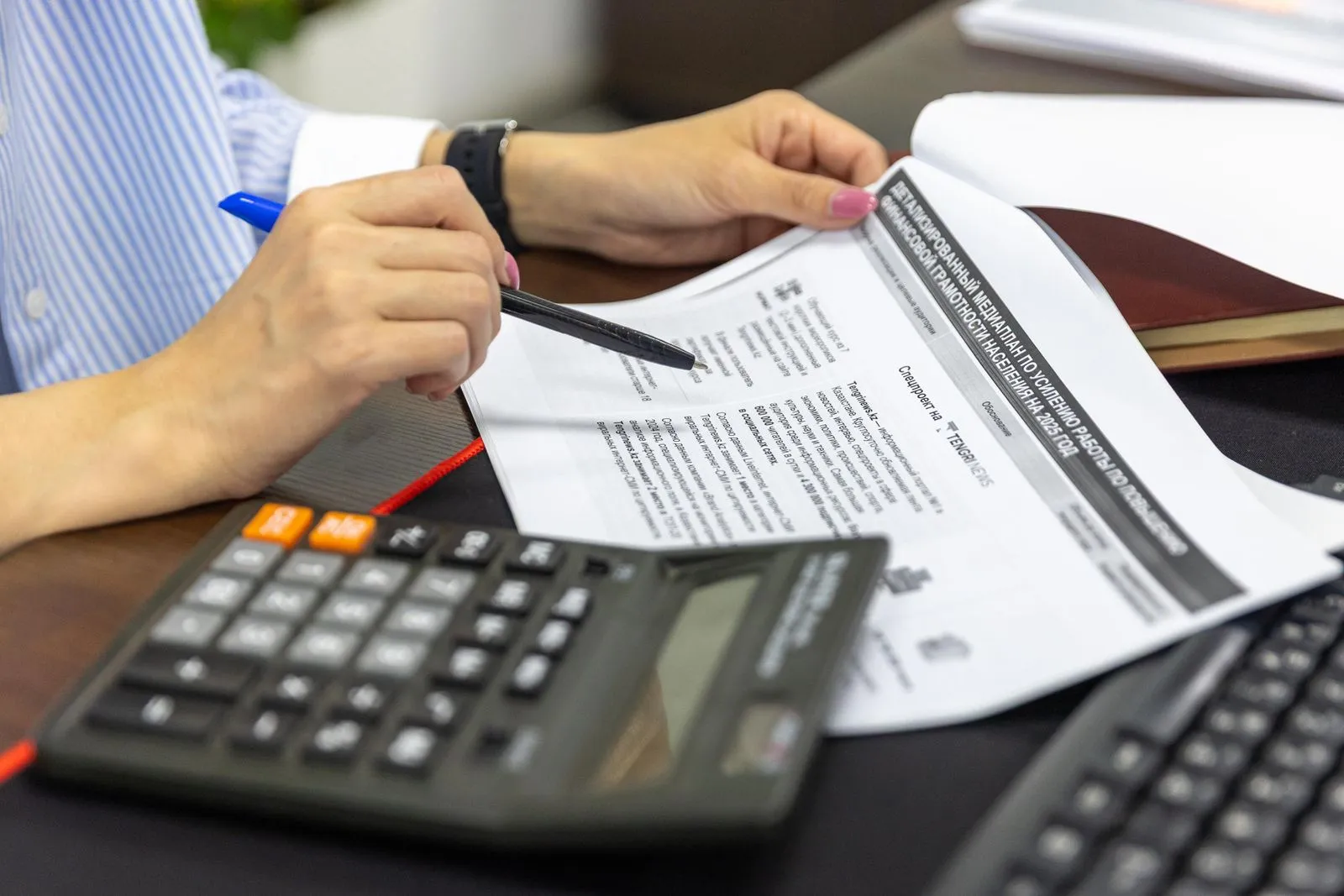 Hands reviewing a document beside a calculator.
