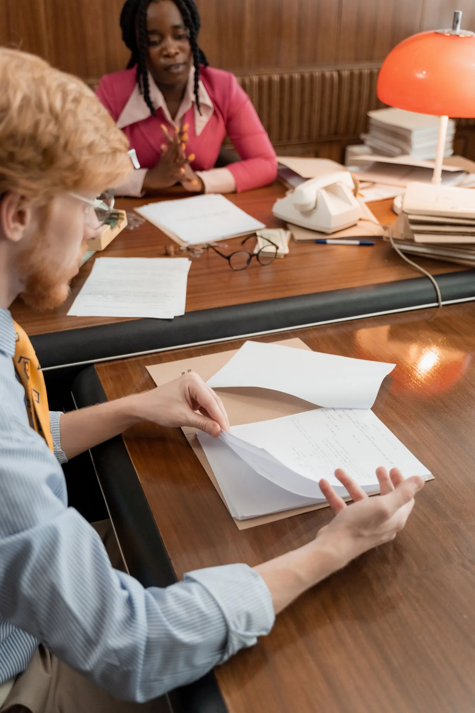 Two colleagues reviewing documents together at a desk.