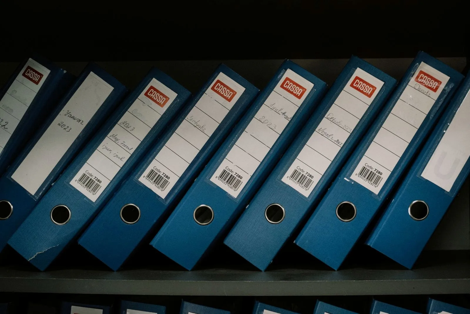 Labeled binders arranged on an office shelf.