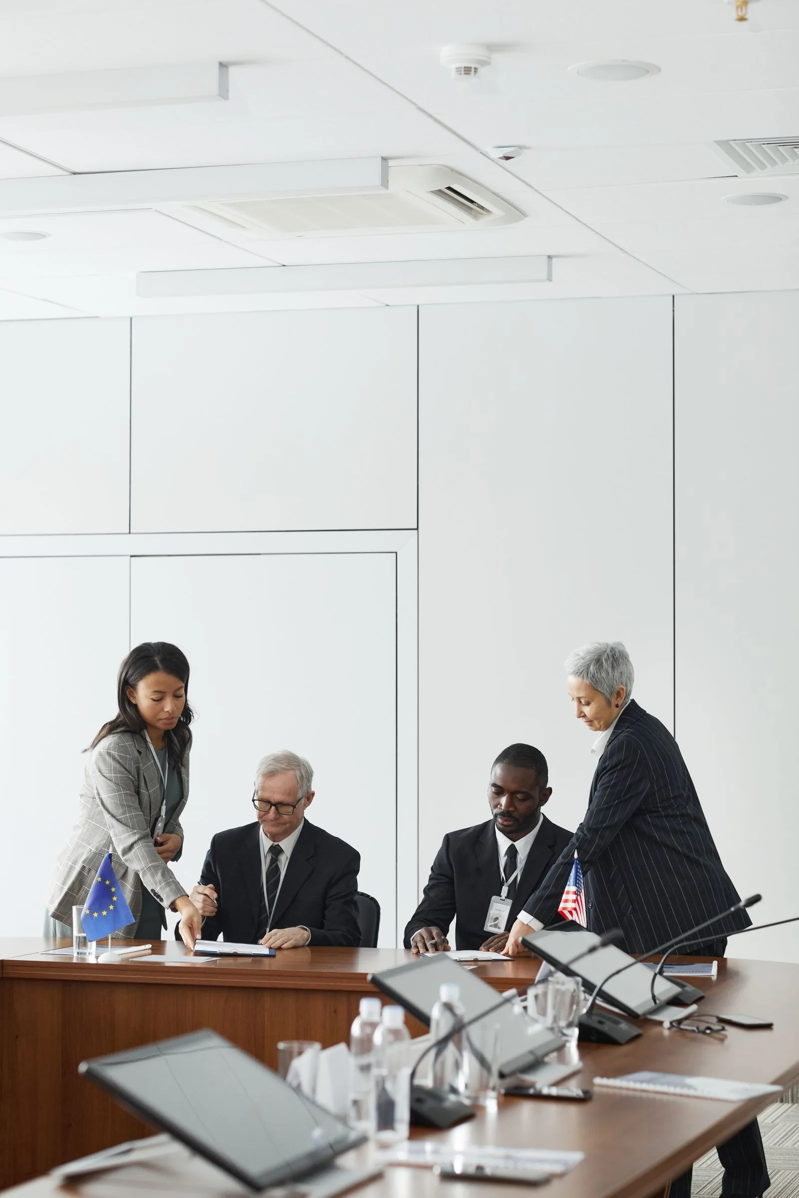 Officials in discussion at a formal meeting table.