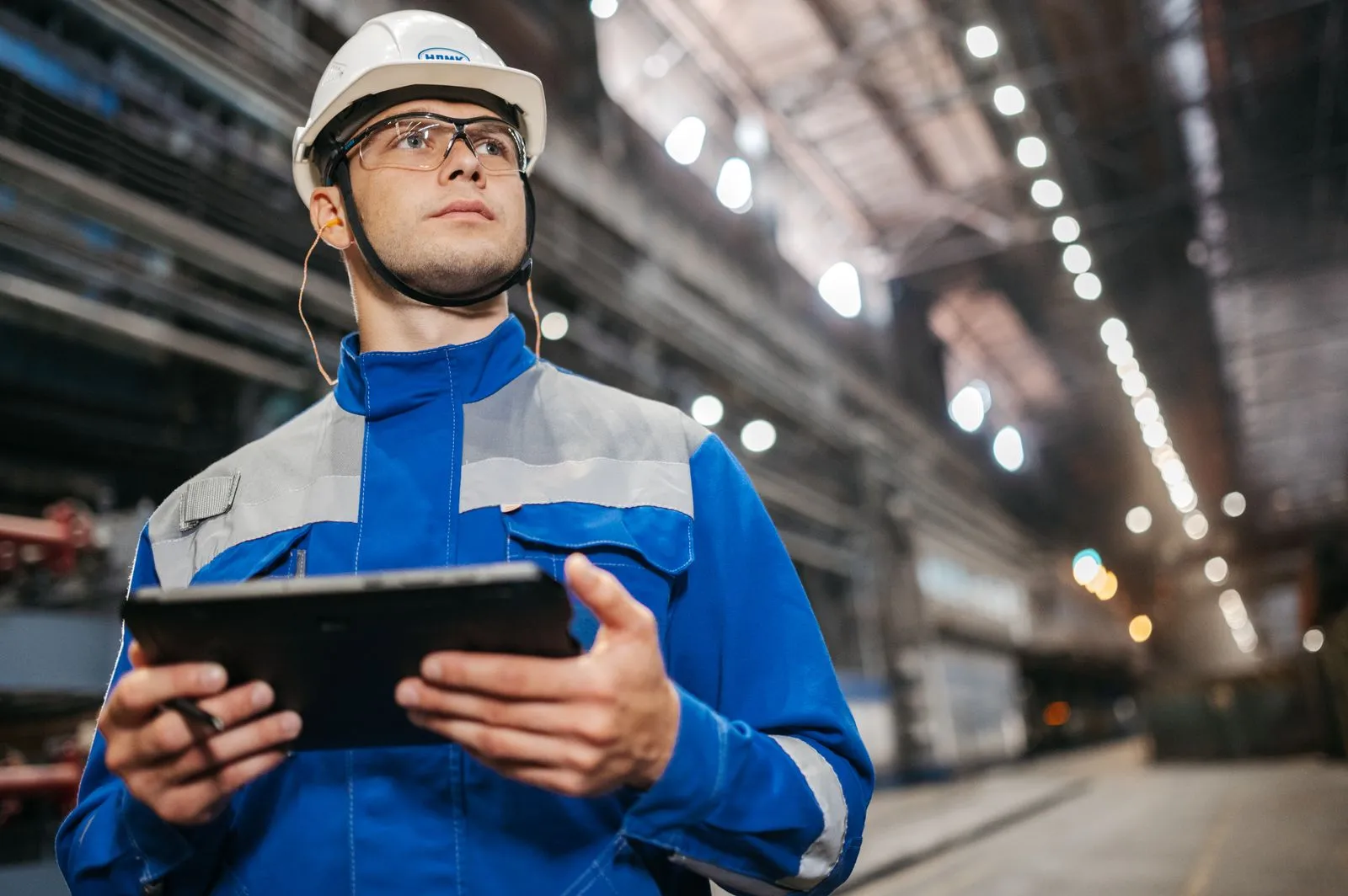 A factory worker consulting a tablet during an inspection.