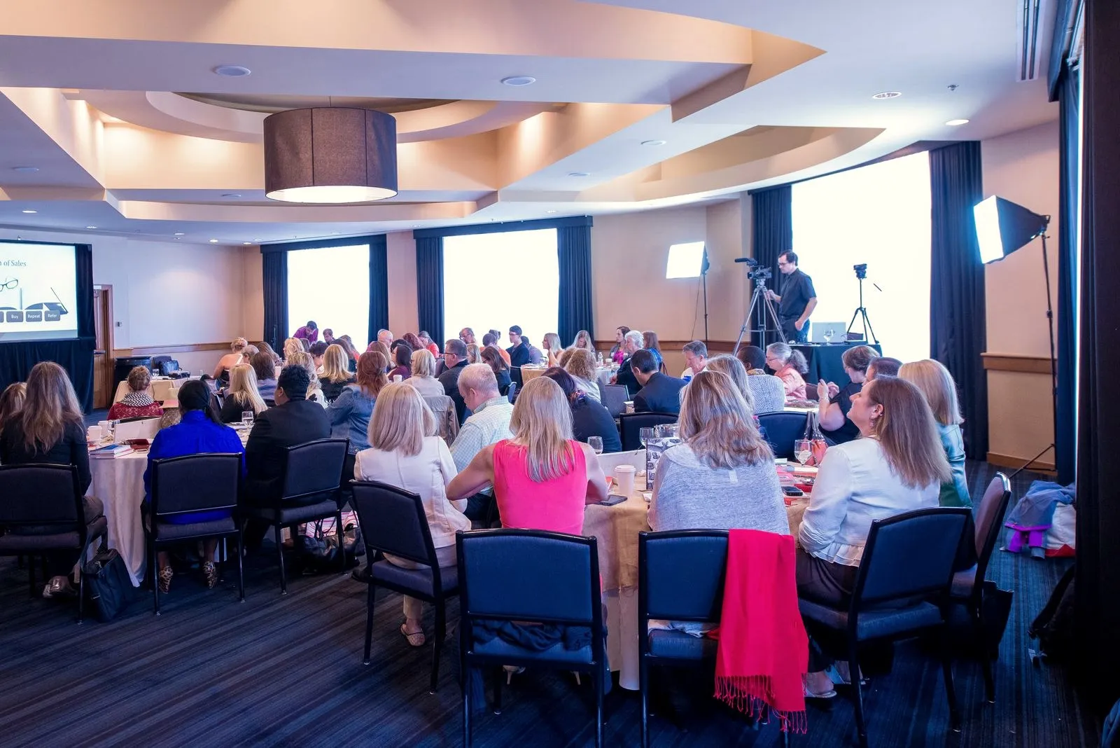 People attending a seminar in a large room.
