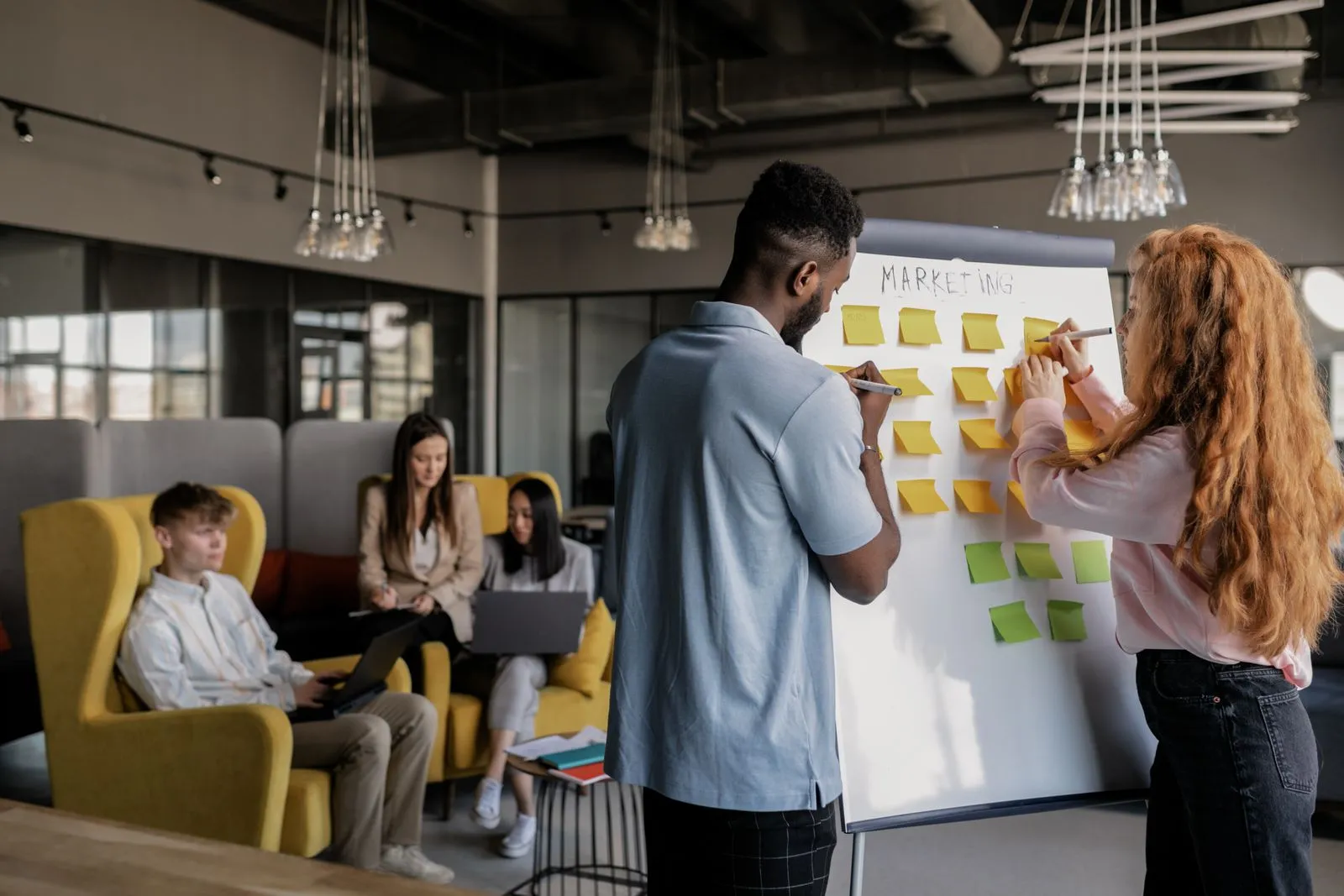 Colleagues planning with sticky notes on a board.