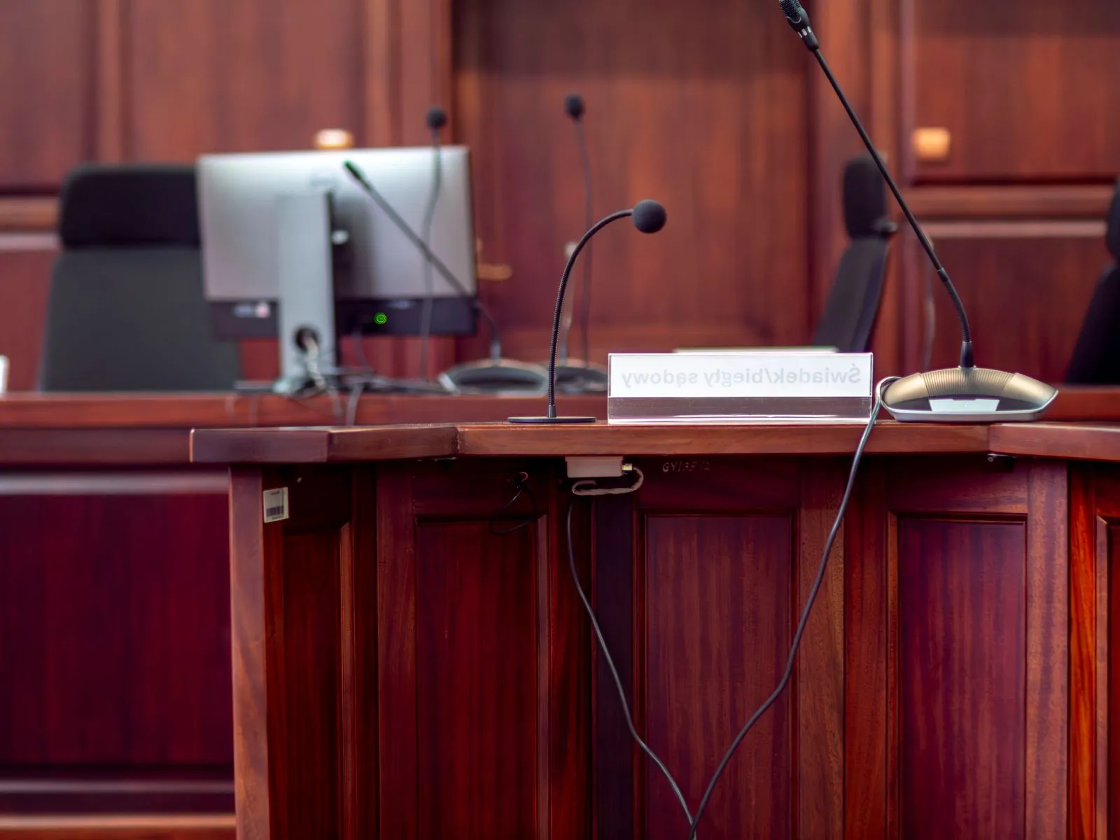 A wooden courtroom podium with microphones.