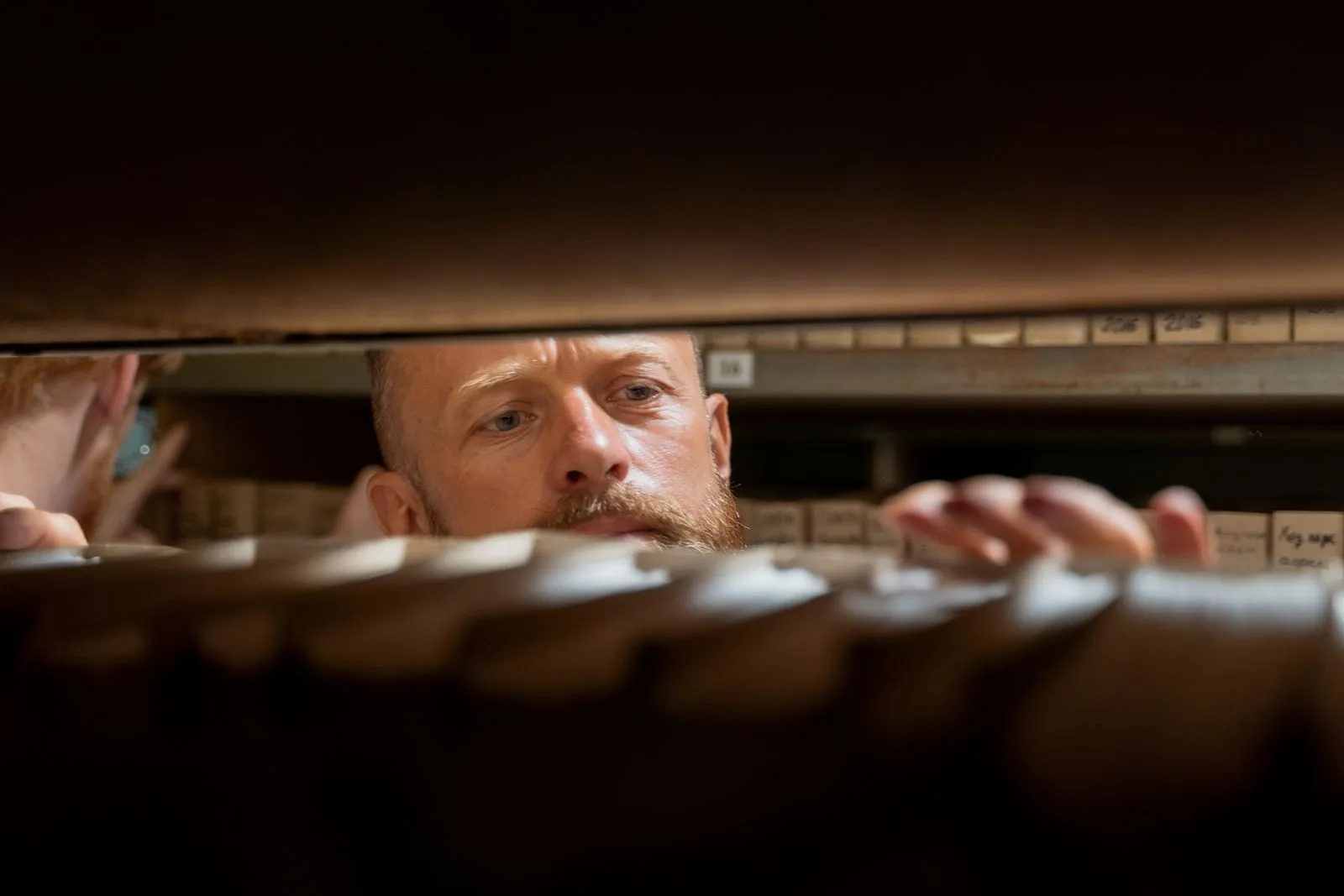 A person searching through archive shelves.